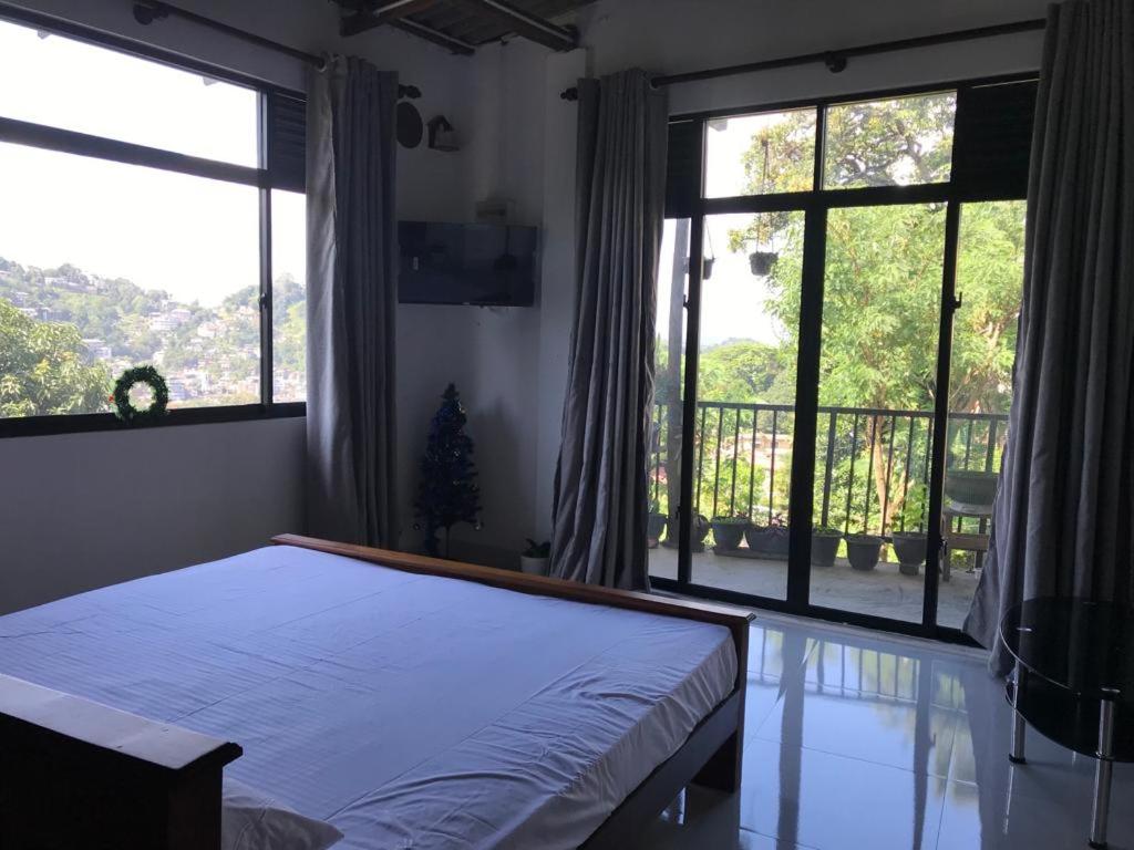 a bedroom with a bed and a balcony with windows at Sky home stay in Kandy