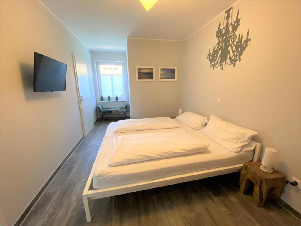 uma cama branca num quarto com uma televisão em FriesenART em Norddeich