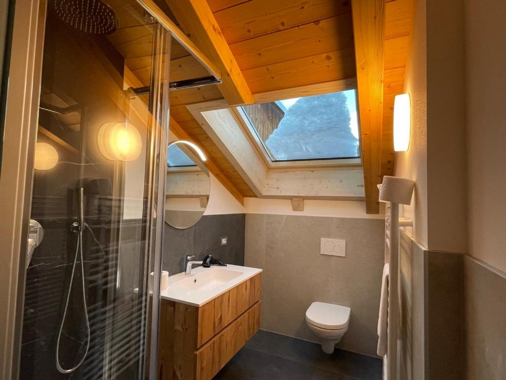 a bathroom with a sink and a toilet and a skylight at Appartamento Rio Duron in Campitello di Fassa