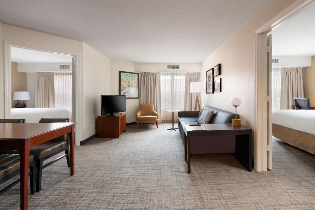 a hotel room with a bed and a couch and a desk at Residence Inn by Marriott Rogers in Rogers