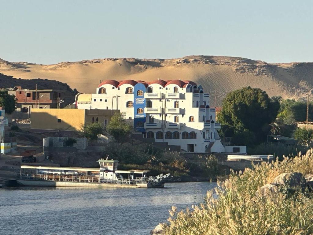 a large white building on the side of a river at ACHERTOD NUBIAN HOTEL in Naj‘ al Maḩaţţah
