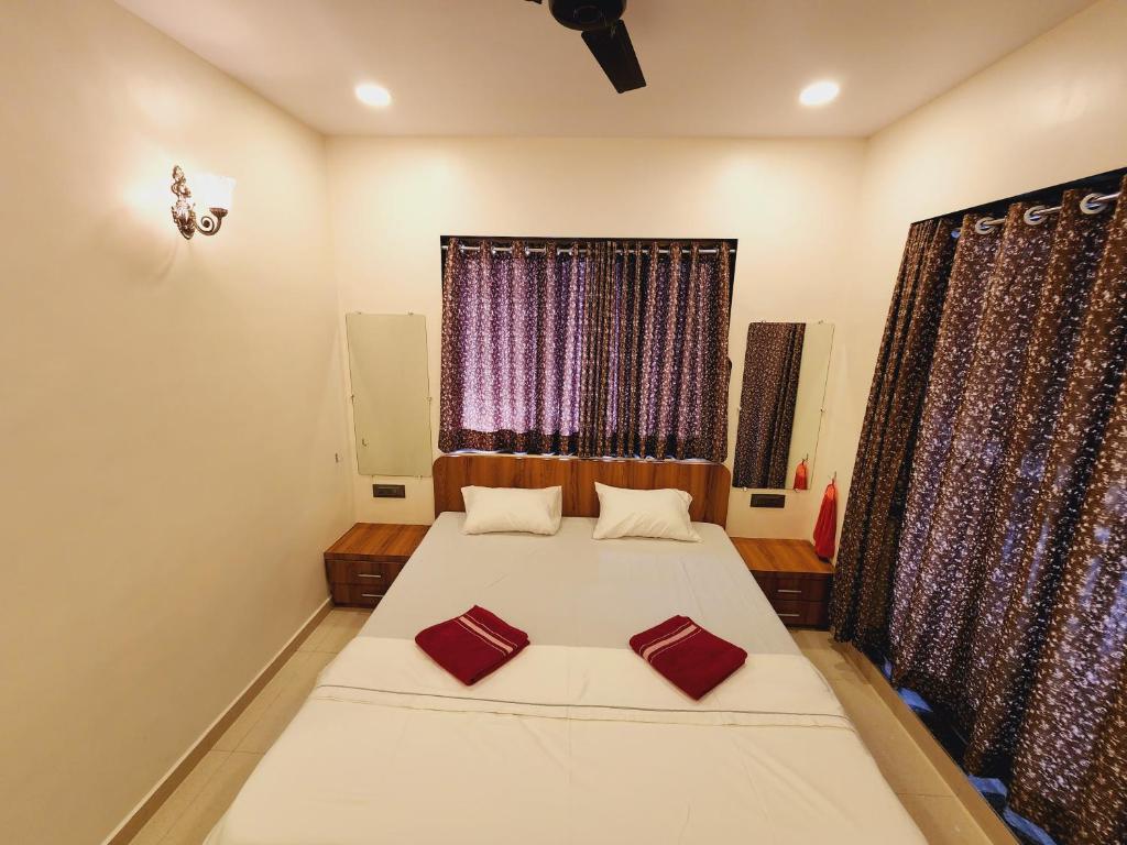 a bedroom with a large bed with red pillows on it at Hotel Mahadev Family Lodging and Boarding in Neral