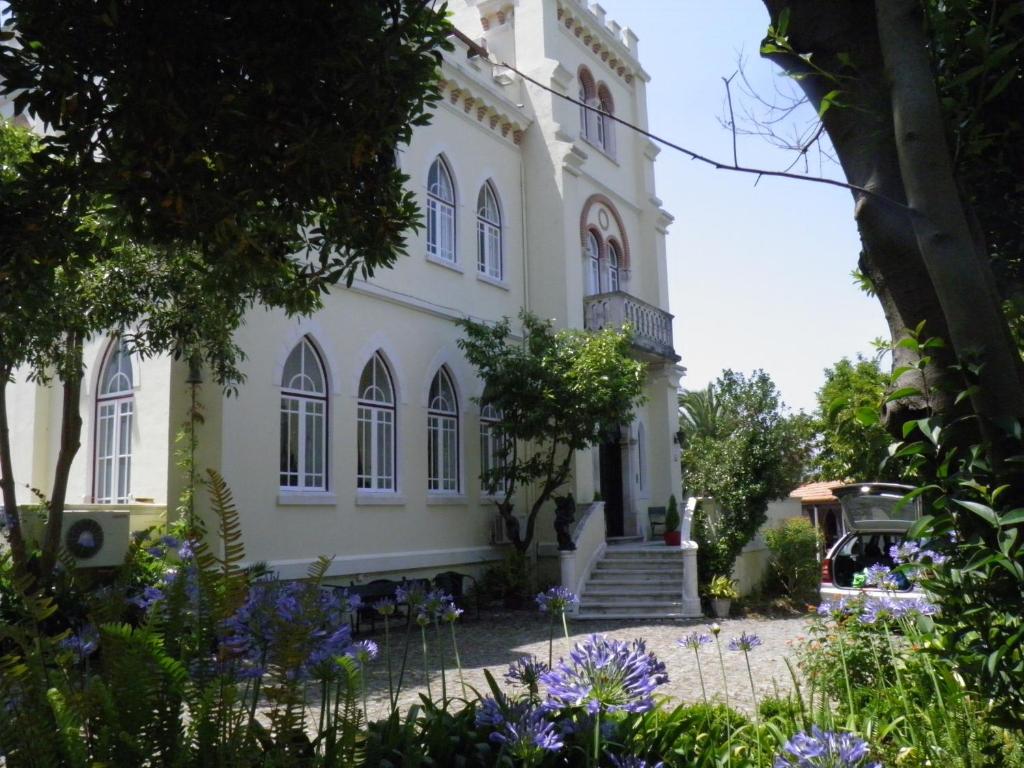 a large white building with windows and purple flowers at Vila Aurora in Luso