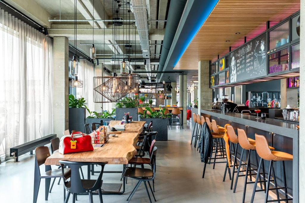 a restaurant with wooden tables and chairs and a bar at Moxy Utrecht in Utrecht