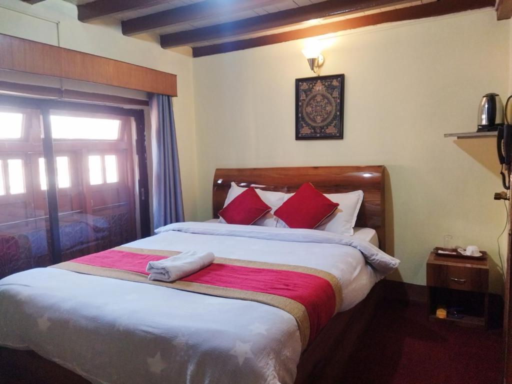 a bedroom with a large bed with red pillows at HOTEL RUPAKOT AND ROOFTOP RESTAURANT in Bhaktapur