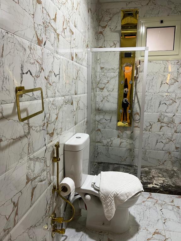 a white bathroom with a toilet and marble walls at Pyramids Top Inn in Cairo