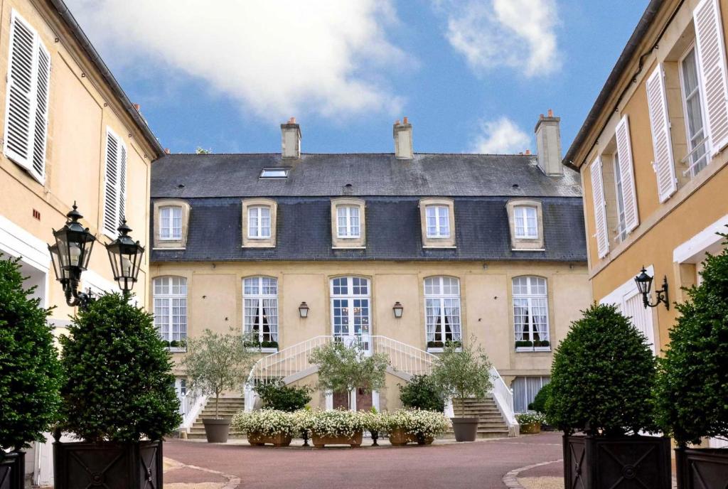 un grand bâtiment avec un toit gris et des escaliers dans l'établissement Hôtel d'Argouges, à Bayeux