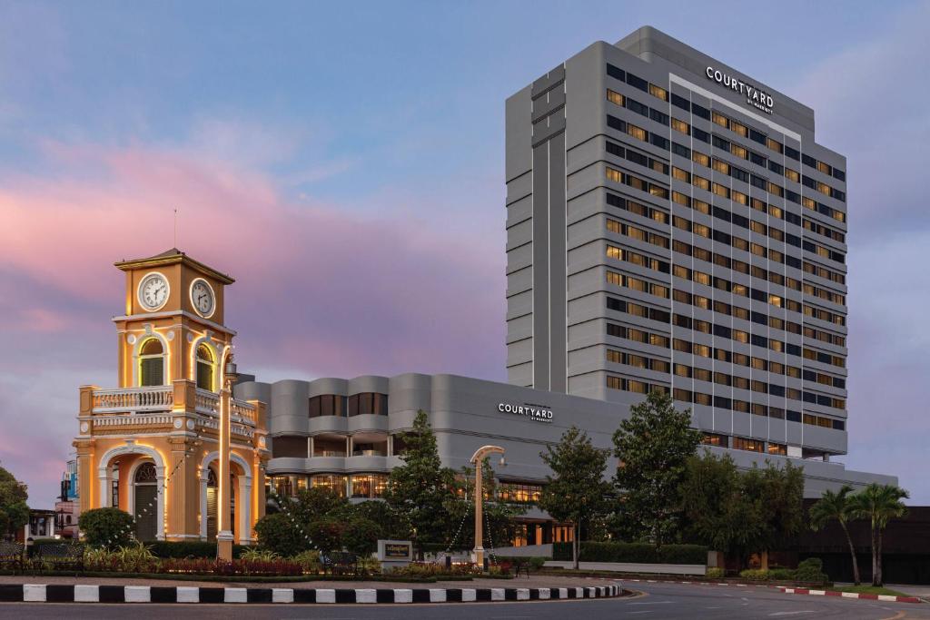 ein Gebäude mit einem Uhrturm vor einem Gebäude in der Unterkunft Courtyard by Marriott Phuket Town in Phuket