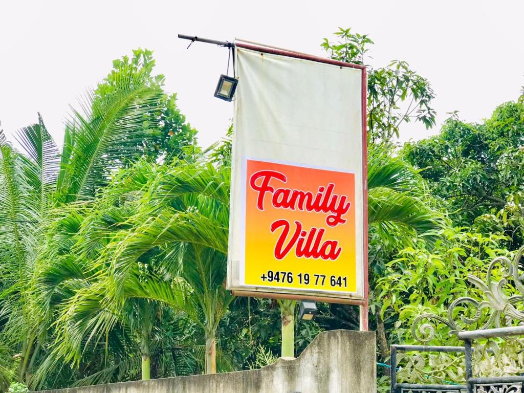 Family Villa Mirissa في ميريسا: علامة لقرية عائلية أمام الأشجار
