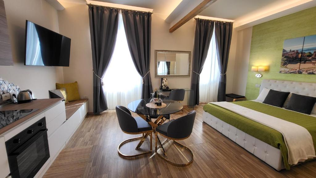 una camera d'albergo con letto, tavolo e sedie di I Due Grifoni Studio Flat a Taormina