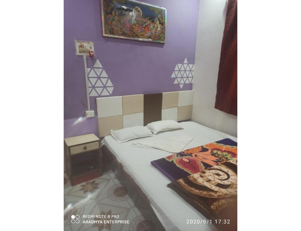 Cama en habitación con pared púrpura en Hotel Roxy DX, Gaya, Bihar en Gaya