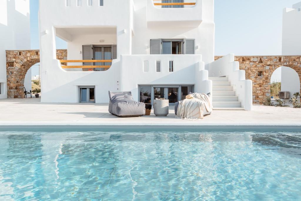 een paar in stoelen naast een zwembad bij Nymphée Luxury Villas in Agia Anna Naxos