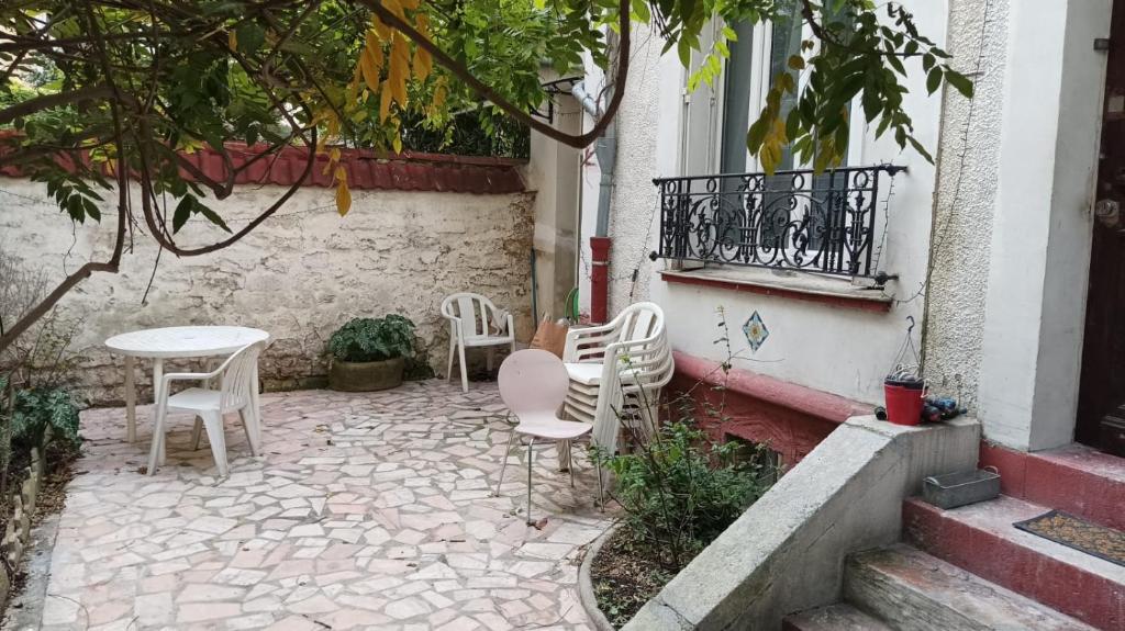 een patio met stoelen, een tafel en een raam bij Garibaldi mini-maison jardin in Saint-Ouen