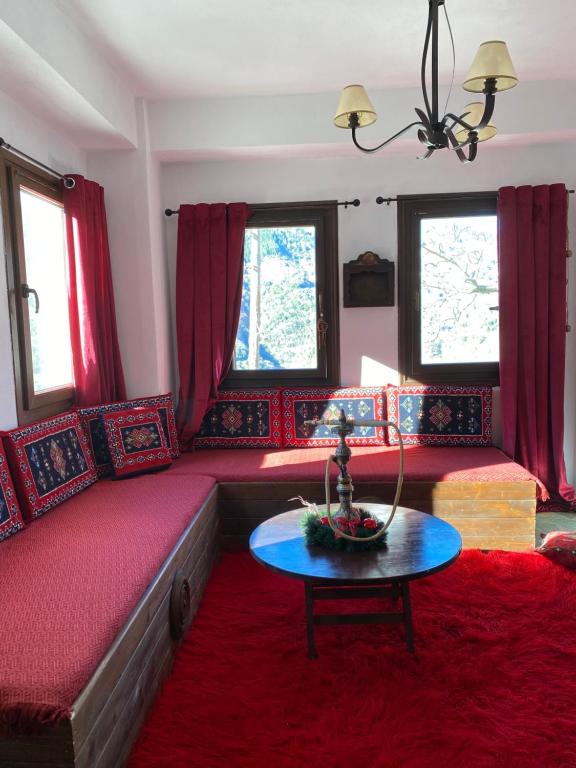 sala de estar con sofá rojo y mesa en La casa Varsani, en Anilio - Metsovo