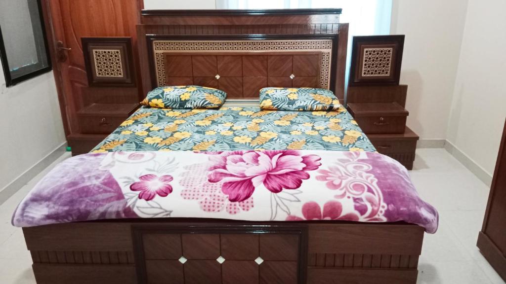 1 Schlafzimmer mit einem Bett mit Blumenbettdecke in der Unterkunft Saadi Guest House in Karatschi