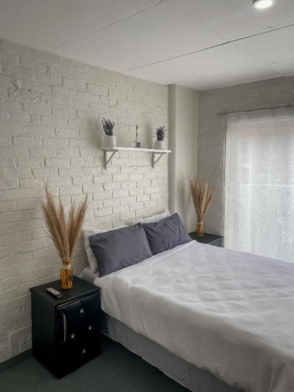 a bedroom with a large bed and a white brick wall at At Home Maboneng in Johannesburg