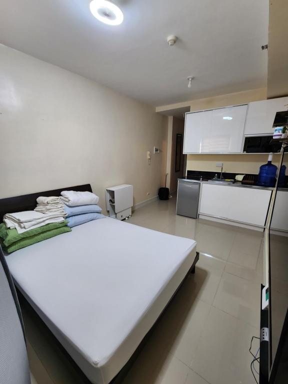 a white bed in a room with a kitchen at Budget price condo near IT Park & Ayala, Cebu City in Cebu City