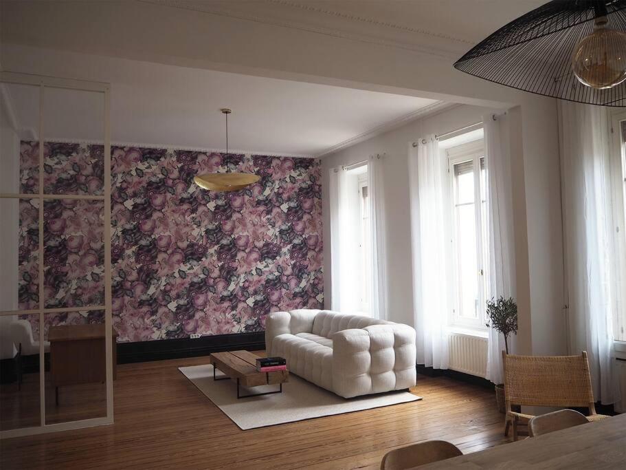 ein Wohnzimmer mit einem weißen Sofa und einer Blumenwand in der Unterkunft Appart design au cœur de Belfort in Belfort