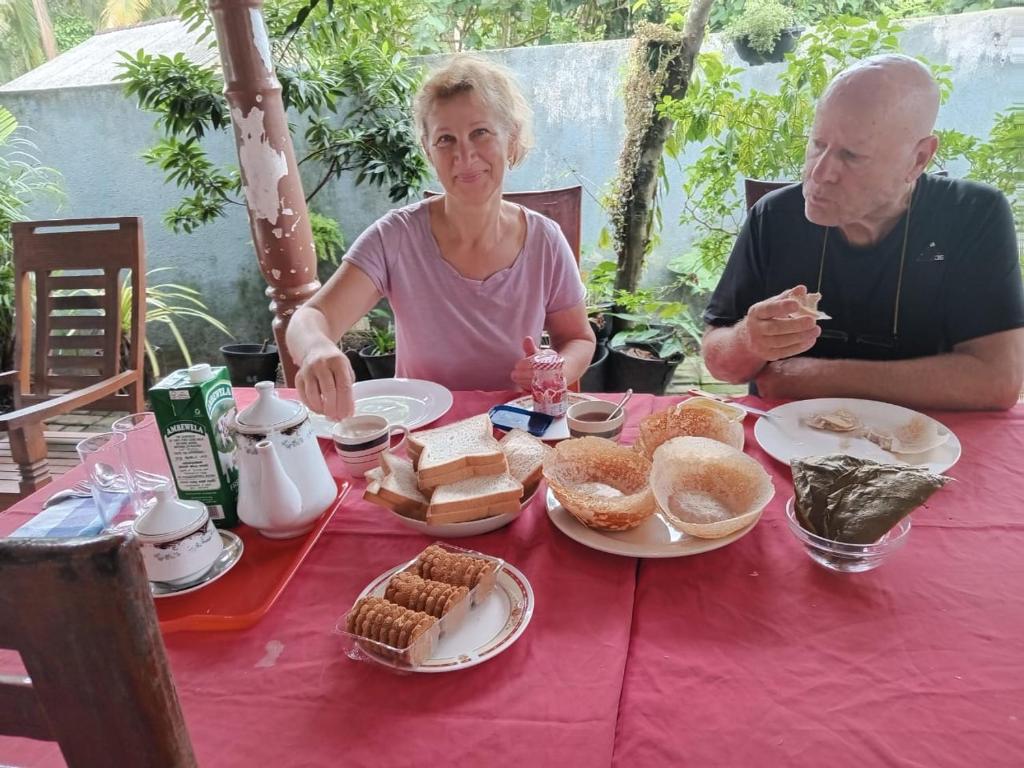 un hombre y una mujer sentados en una mesa con comida en Little Villa Guest House en Ahangama