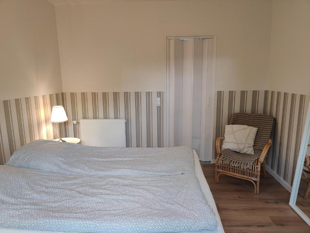 a bedroom with a bed and a chair and a lamp at Pension Skovly in Tranekær