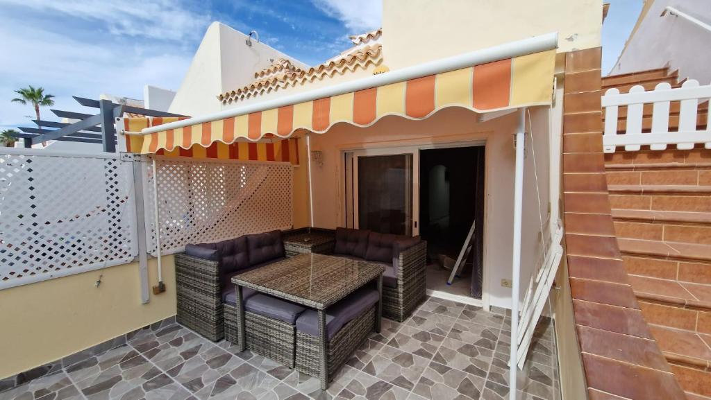 un patio con sillas y toldo en una casa en The Palms Golf Del Sur - Casa Andromeda, en San Miguel de Abona