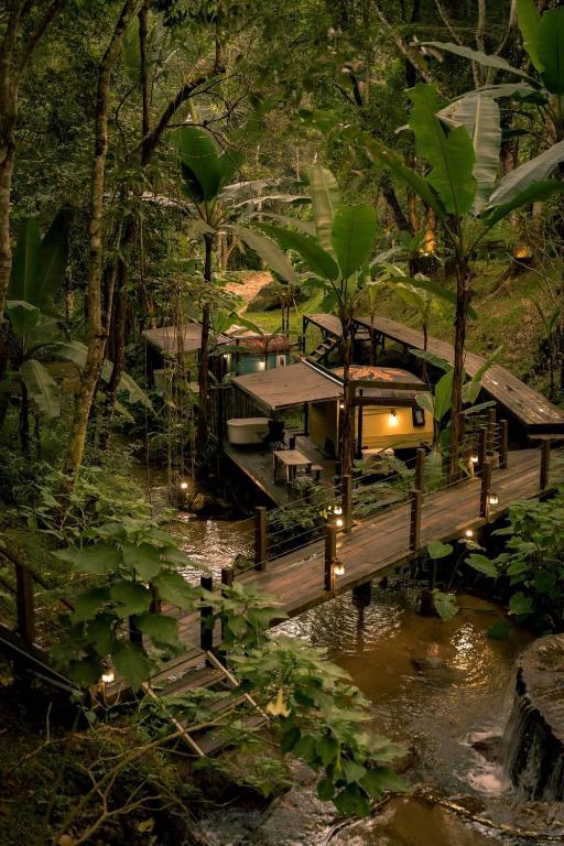 a train crossing a bridge over a river in a forest at Voraman B-One in Chiang Mai