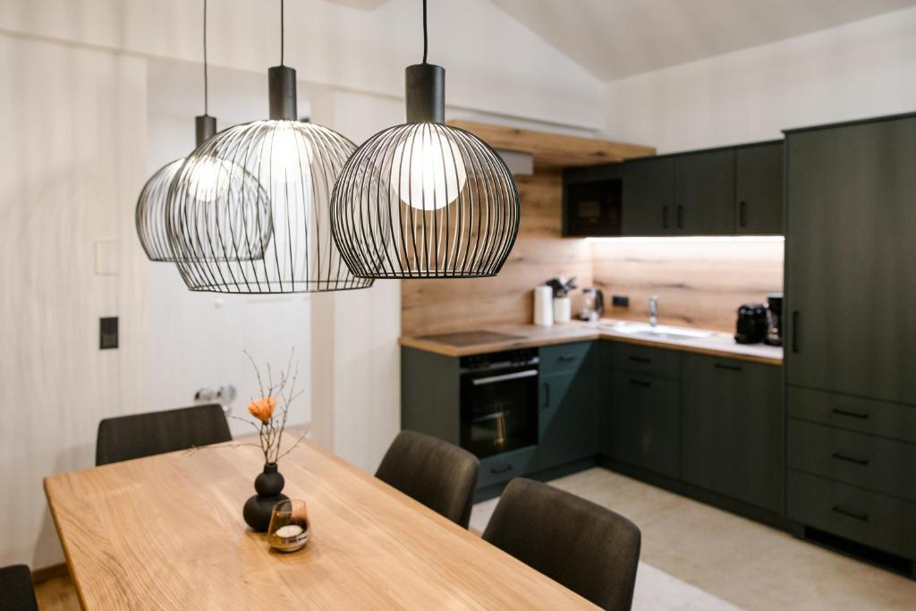 une cuisine avec une table en bois et deux lampes suspendues dans l'établissement ANN SUITES Appartements, à Filzmoos