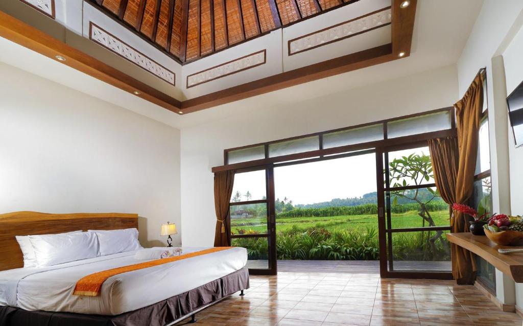 a bedroom with a bed and a large window at Lumbung Asri Cottage in Mambat