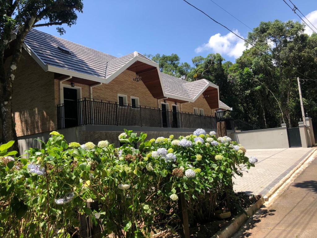 a house with flowers in front of a fence at Casa X in Campos do Jordão