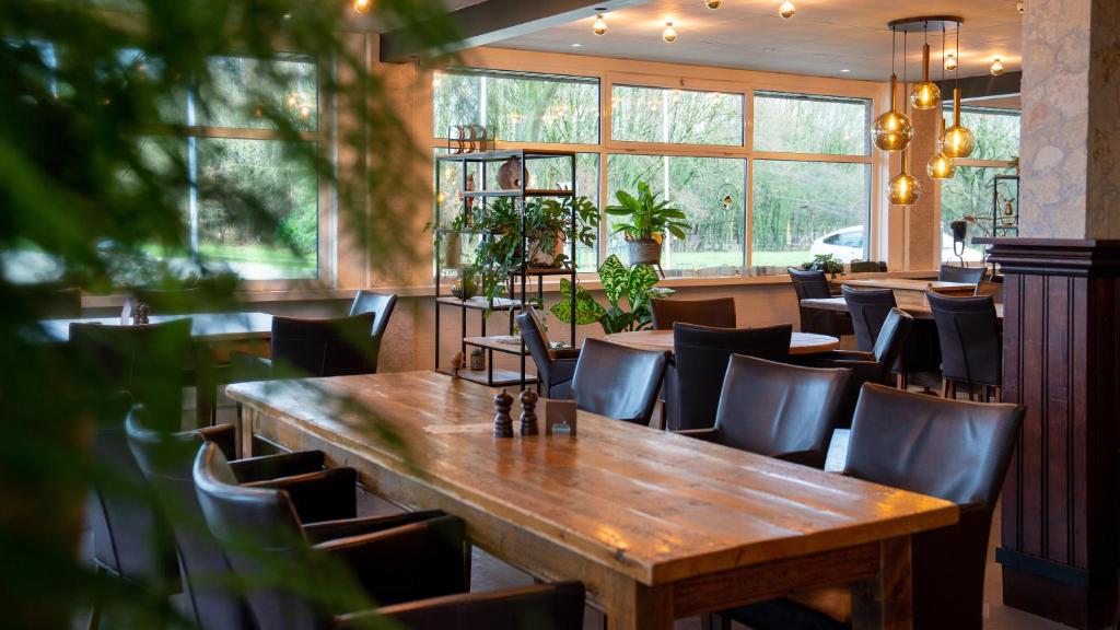 een eetkamer met een houten tafel en stoelen bij Hotel Martensplek in Tiendeveen