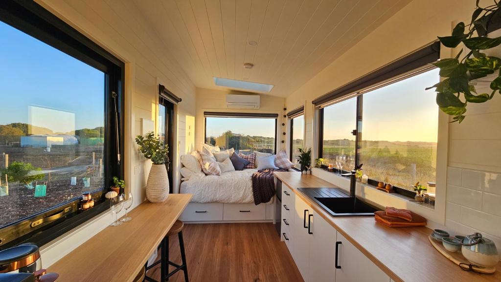 a bedroom with a bed and large windows at Sunset Haven - port fairy tiny homes in Killarney