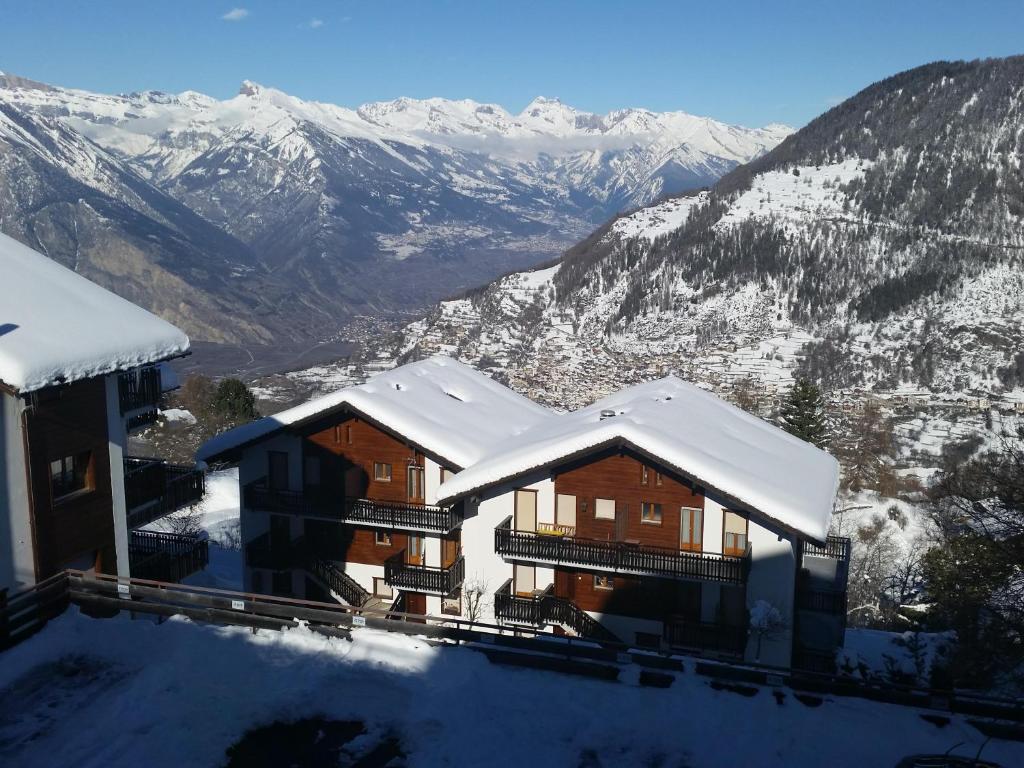 a house with snow covered roofs with mountains in the background at Appartement Arolles 701 in La Tzoumaz