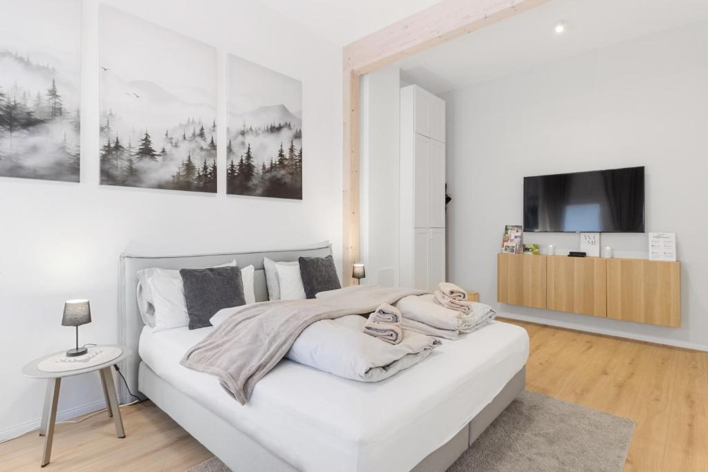 a white bedroom with a large white bed and a tv at Winetime - modern - luxuriös - direkt im Zentrum - Netflix in Landau in der Pfalz