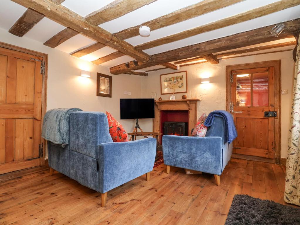 a living room with two blue chairs and a television at Winter Cottage in Sudbury