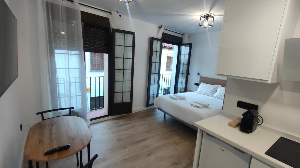 a room with a bed and a kitchen with windows at MiRa San Basilio in Córdoba