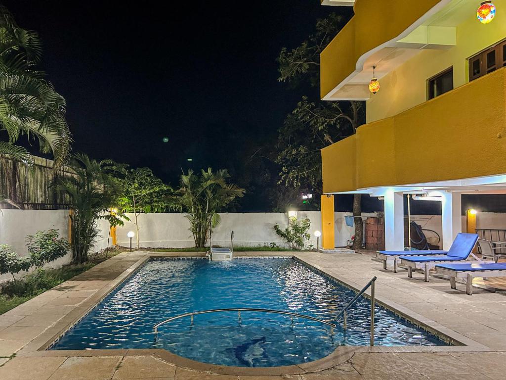 a swimming pool in front of a house at night at LA Costa Residency in Anjuna