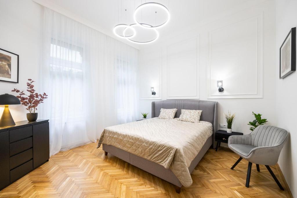 a white bedroom with a bed and a chair at Luxurious Central 4BEDRM 3BATHRM Residence w/ Balcony in Budapest