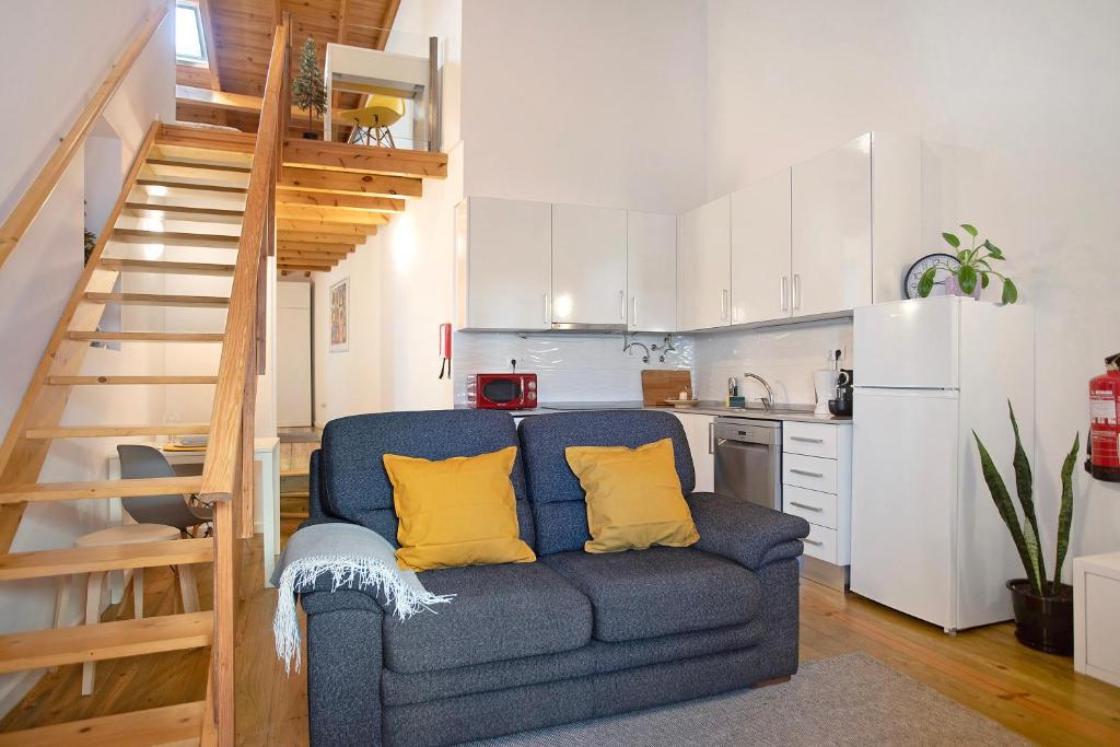 a living room with a blue couch and a kitchen at Casinha Da Vila Turcifal in Turcifal