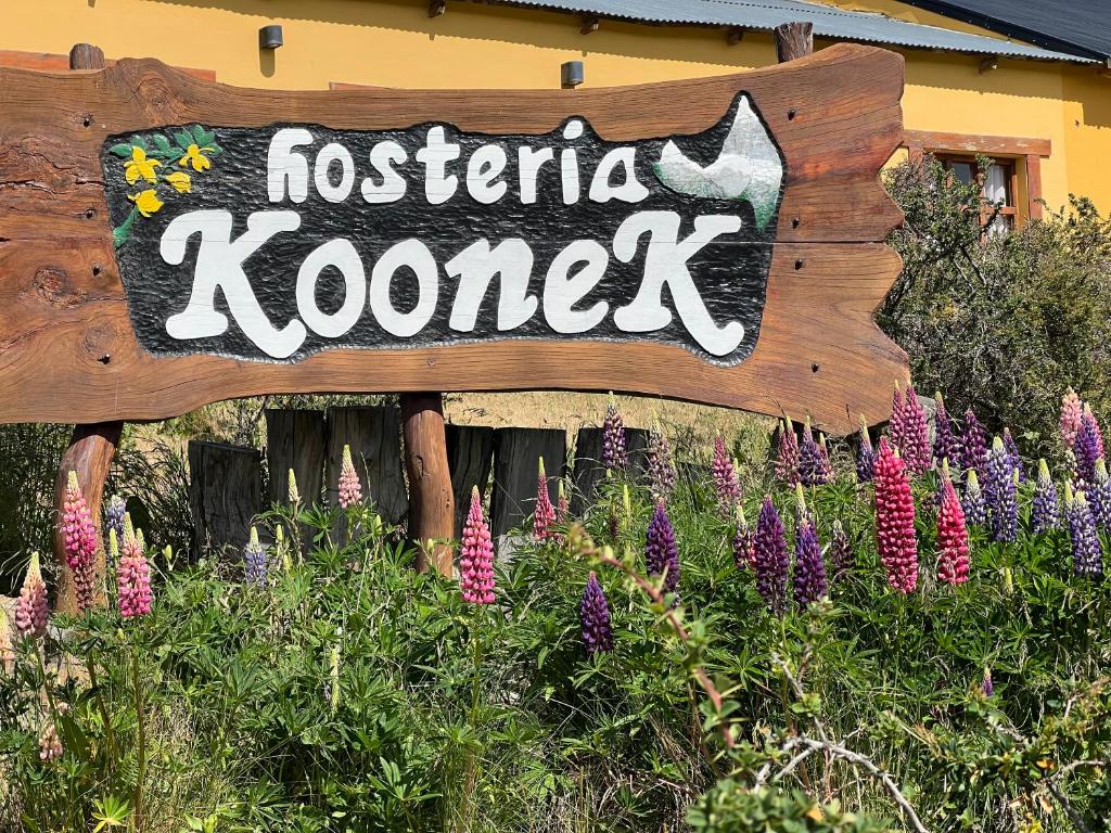un cartello per una calzieria kotek di fronte ai fiori di Hosteria Koonek a El Chalten