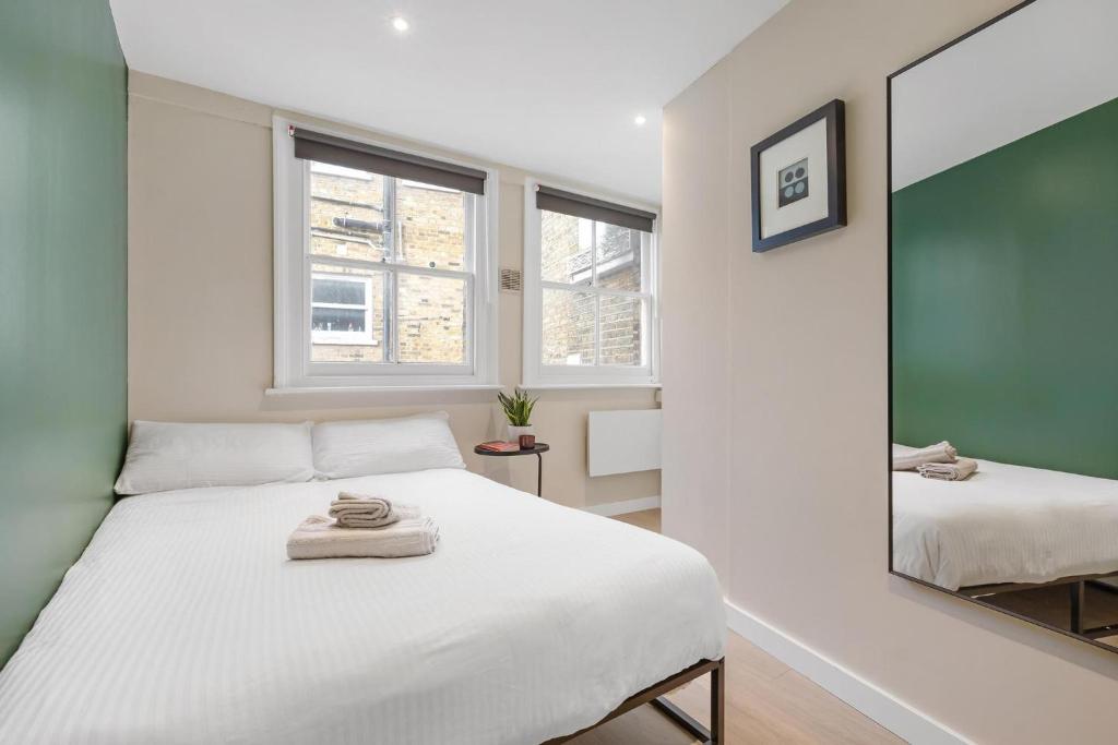 a bedroom with a white bed and a mirror at Quaint Mews Home in Chelsea in London