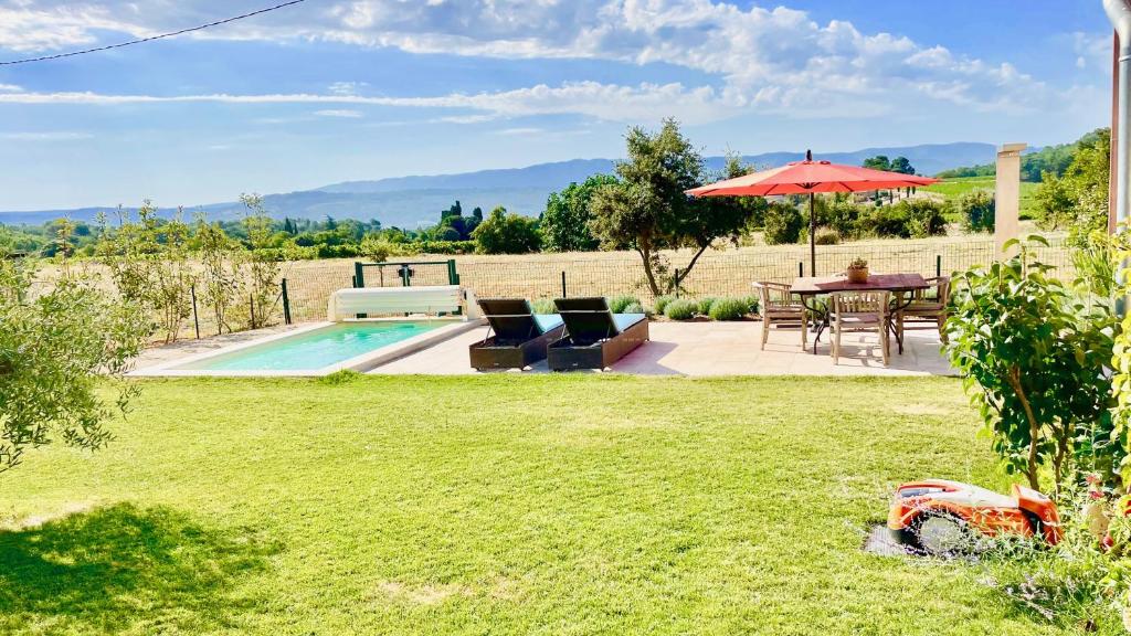 a garden with a table and an umbrella and a pool at La Belle Lumière in Saint-Saturnin-lès-Apt