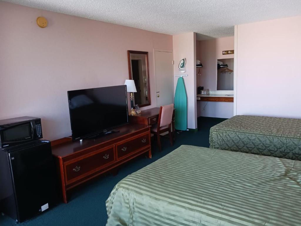 a hotel room with two beds and a flat screen tv at BlissPoint Inn Wabash in Wabash