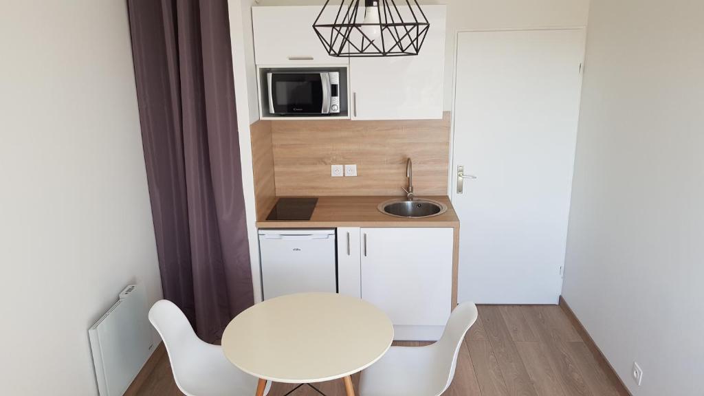 une petite cuisine avec une table et des chaises blanches dans l'établissement IKIZEN - Arena Confort - Boulingrin, à Reims