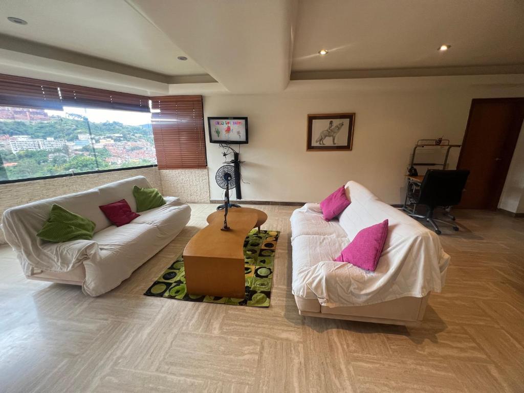 uma sala de estar com 2 sofás brancos e almofadas cor-de-rosa em Río de Oro em Caracas