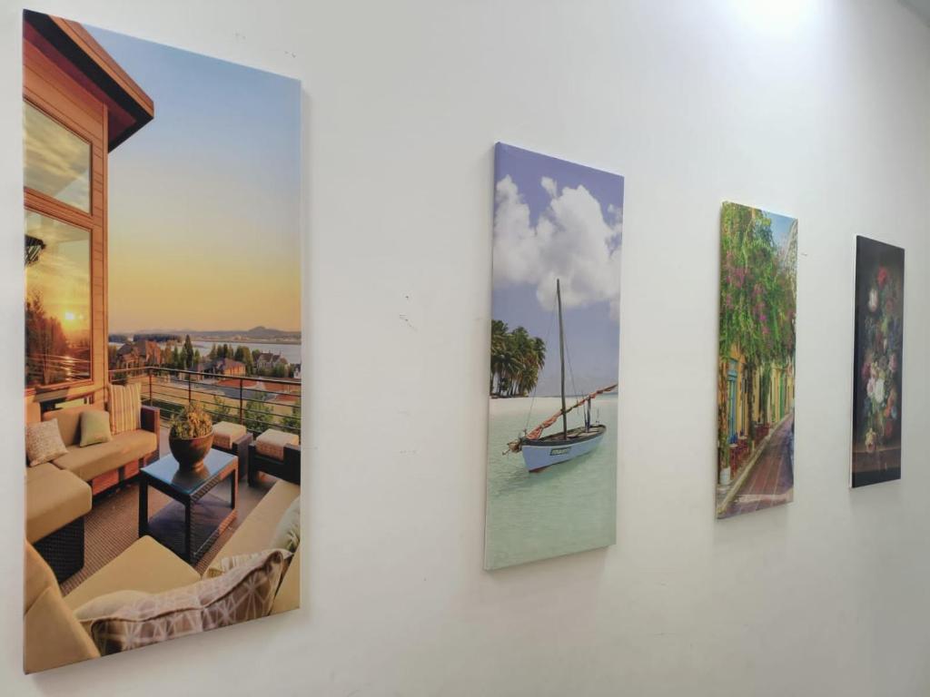 a group of three paintings hanging on a wall at alshahad chalet in Bārsit