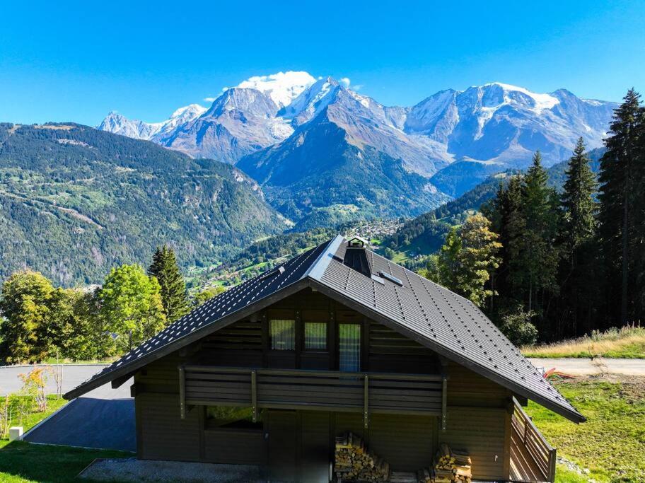 une maison avec un toit et des montagnes en arrière-plan dans l'établissement Chalet Anatole - Vue Mont Blanc Exceptionnelle, à Saint-Gervais-les-Bains