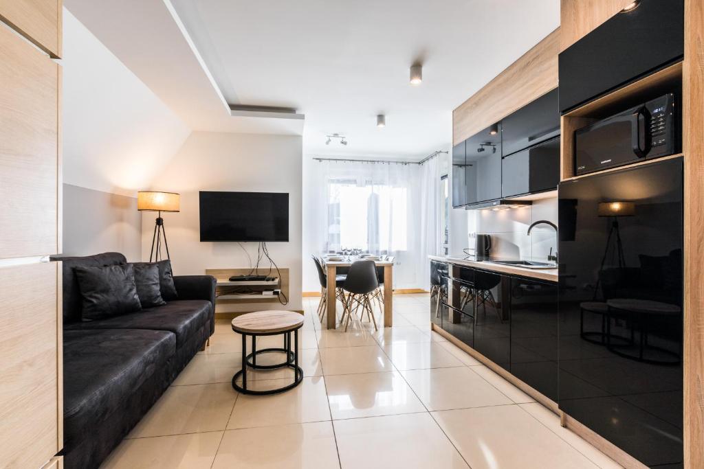 een woonkamer met een zwarte bank en een keuken bij Apartament Levante in Zakopane