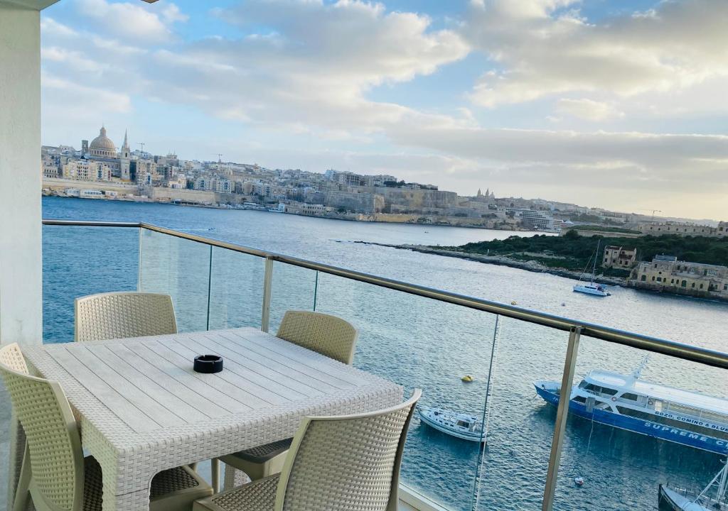 einen Tisch und Stühle auf einem Balkon mit Blick auf das Wasser in der Unterkunft Sliema Seaview & seafront- APT 9, 49 Tigne Point Mansions in Sliema