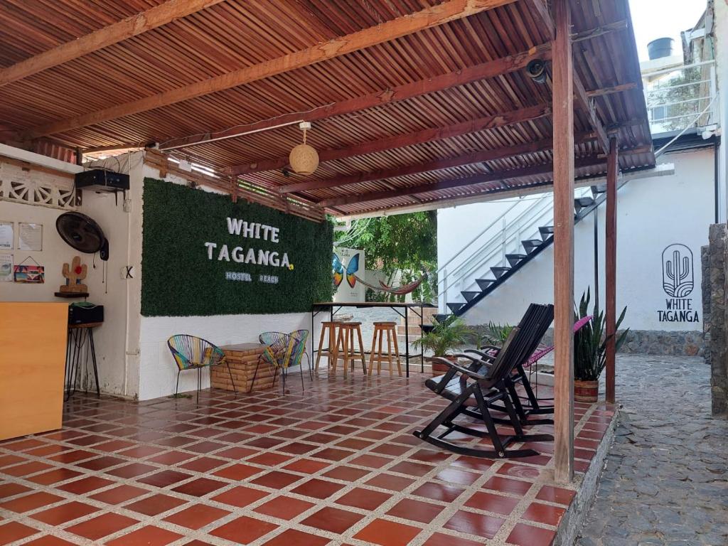 eine Terrasse mit Stühlen und ein Schild mit weißem Tarzan in der Unterkunft White Taganga in Taganga