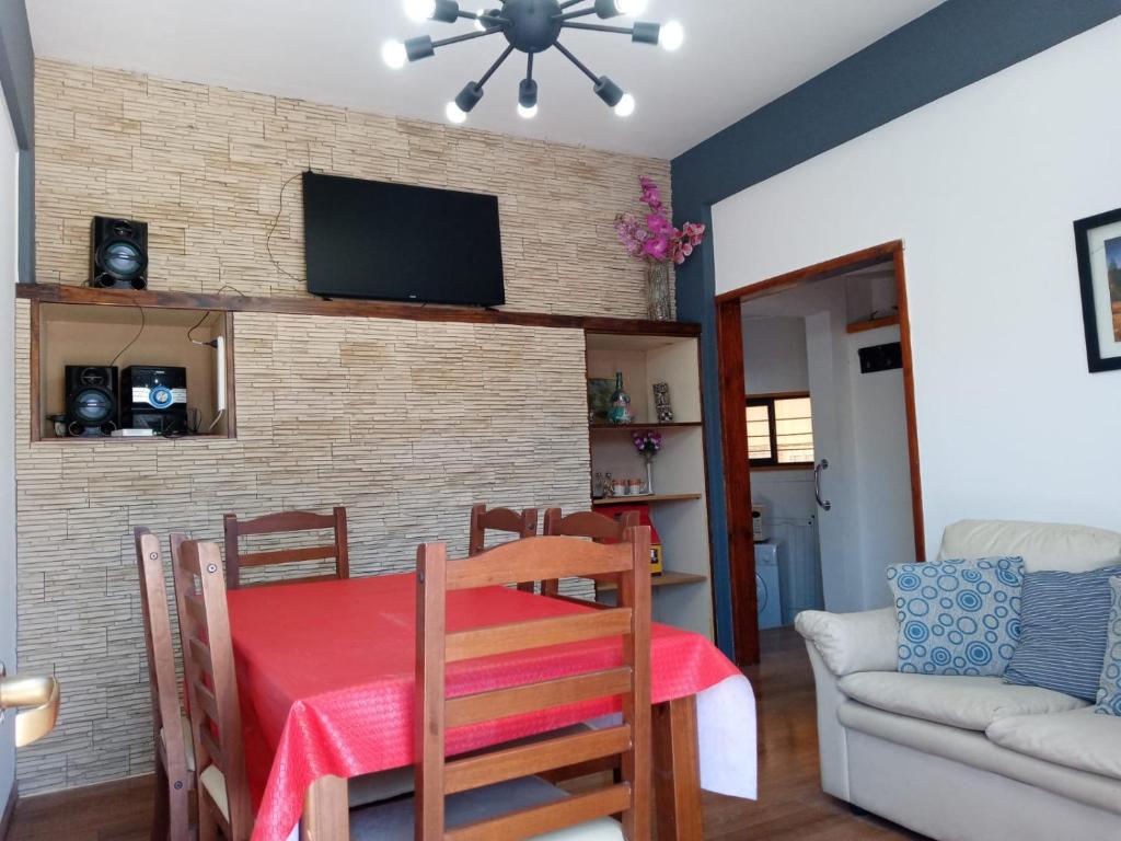 a dining room with a table and a television on a brick wall at La Casita de Lu in San Carlos de Bariloche